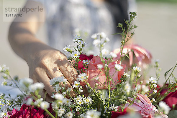 Mitschnitt einer Frau  die Blumen in einem Strauss arrangiert