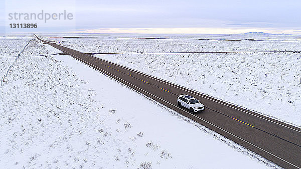 Hochwinkelansicht eines Fahrzeugs  das sich auf der Straße inmitten einer schneebedeckten Landschaft gegen den Himmel bewegt