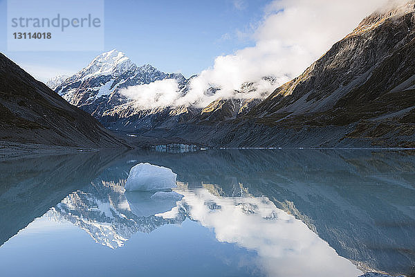 Gletscher im ruhigen Hooker Lake bei Bergen gegen wolkigen Himmel