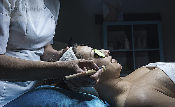Mittelteil einer Kosmetikerin  die der Kundin im ästhetischen Zentrum eine Gesichtsmaske aufsetzt