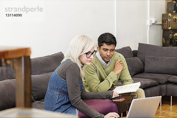 Geschäftsleute  die während einer Besprechung im Kreativbüro einen Laptop benutzen