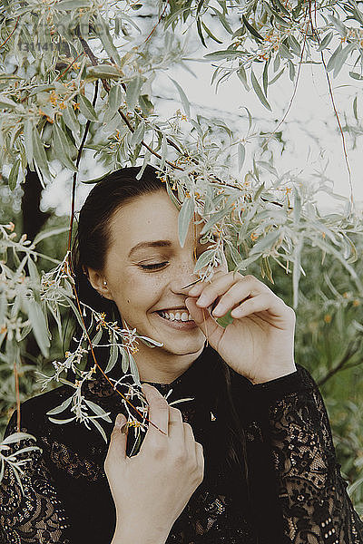 Nahaufnahme einer fröhlichen jungen Frau inmitten von Pflanzen im Park