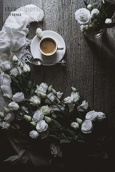 Draufsicht auf Kaffee mit weißen Rosen auf Holztisch