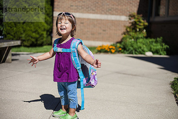 Porträt eines glücklichen Mädchens mit Rucksack  das an einem sonnigen Tag auf einem Wanderweg steht