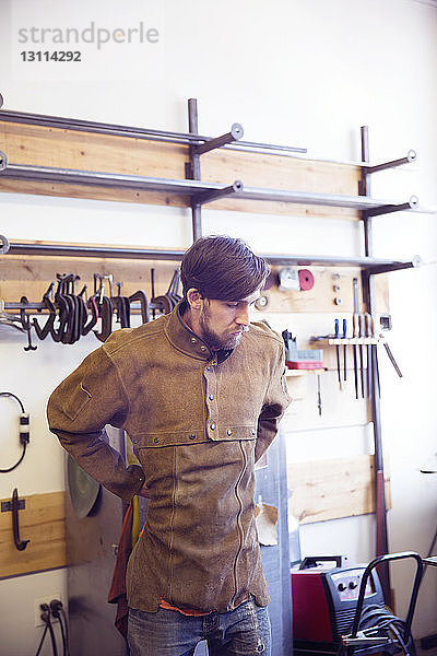 Männlicher Handwerker mit Arbeitsschutzkleidung in einer Holzwerkstatt