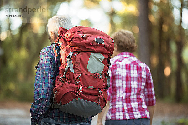 Rückansicht eines älteren Ehepaares beim Wandern im Wald