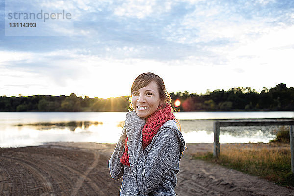 Porträt einer glücklichen Frau  die an einem sonnigen Tag am Seeufer steht