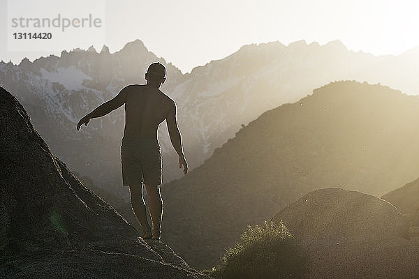 Rückansicht eines Wanderers  der auf dem Berg gegen den Morgenhimmel balanciert