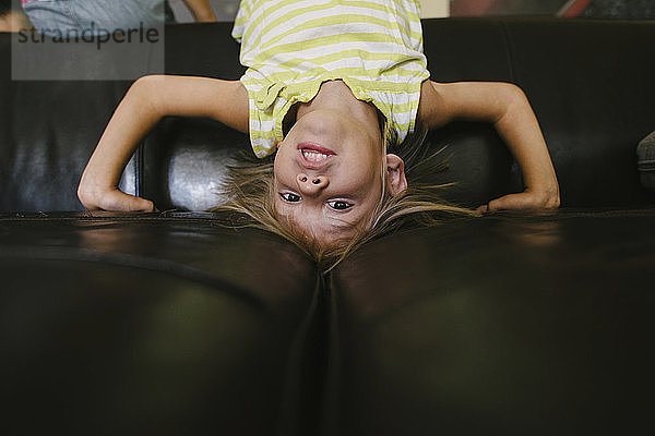 Portrait eines Mädchens auf dem Kopf auf dem heimischen Sofa