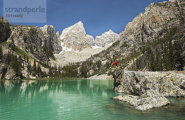 Teenager springt in der Dämmerung in den See gegen Berge