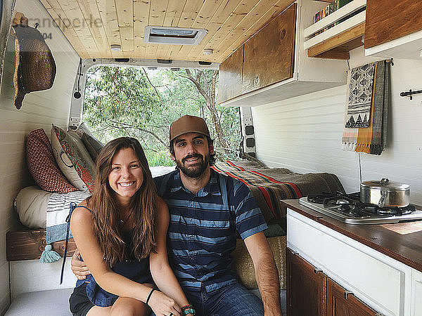 Porträt eines glücklichen Paares  das im Wohnmobil im Wald sitzt