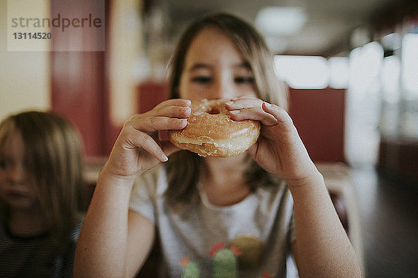 Mädchen isst Donut  während sie zu Hause sitzt