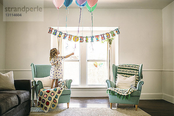 Mädchen dekoriert Luftballons im Wohnzimmer für Geburtstagsfeier