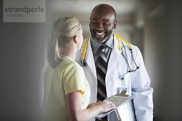 Lächelnder Arzt diskutiert mit Krankenschwester im Krankenhaus