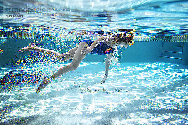 Seitenansicht eines Mädchens  das im Schwimmbad unter Wasser schwimmt