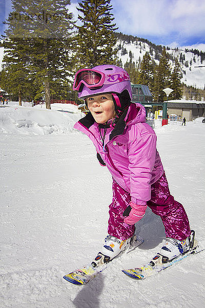 Glückliches Mädchen beim Skifahren auf schneebedecktem Feld