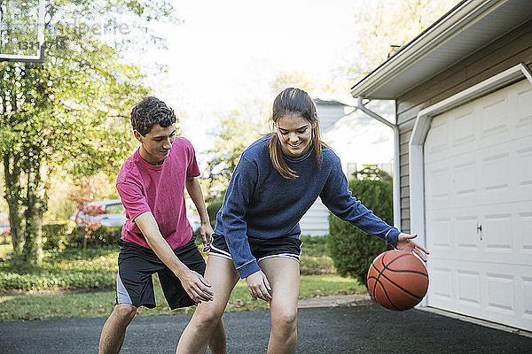 Glückliche Geschwister spielen Basketball im Hinterhof