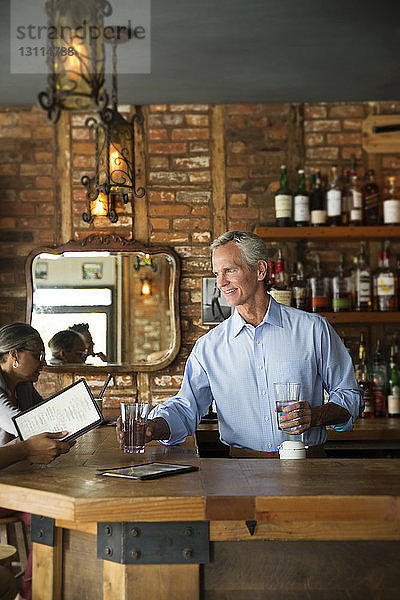 Selbstbewusster Besitzer serviert Kunden Getränke an der Bartheke im Café