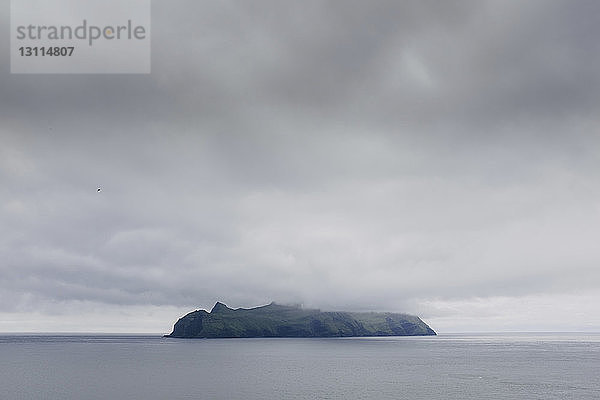 Insel im Meer gegen stürmische Wolken