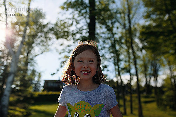 Nahaufnahme-Porträt eines glücklichen Mädchens  das an Bäumen steht