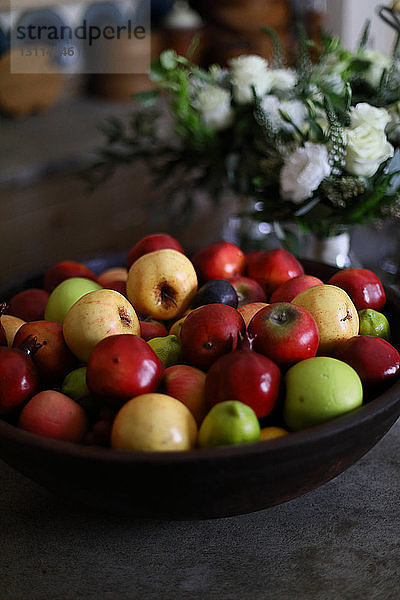 Hochwinkelansicht von Früchten in Schale durch Blumenvase auf dem Tisch