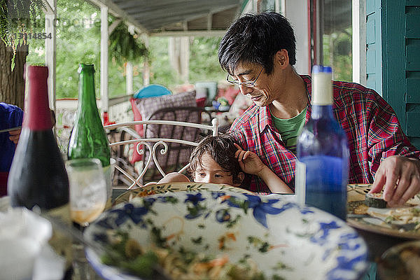 Vater und Sohn beim Mittagessen am Esstisch auf der Veranda