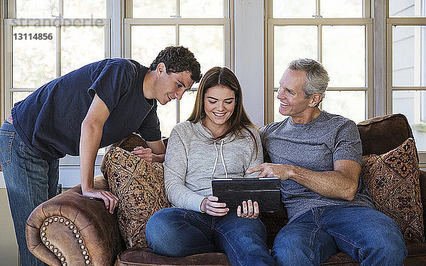 Glückliche Familie schaut zu Hause auf die Tablette