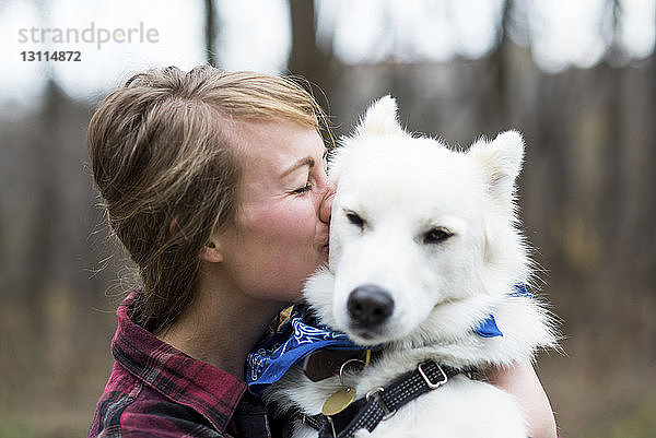 Seitenansicht einer glücklichen Frau  die einen Hund küsst