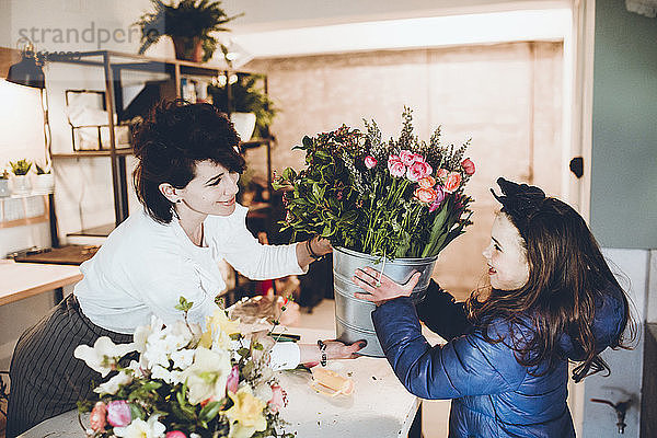 Florist schenkt Mädchen im Laden einen Eimer Blumen