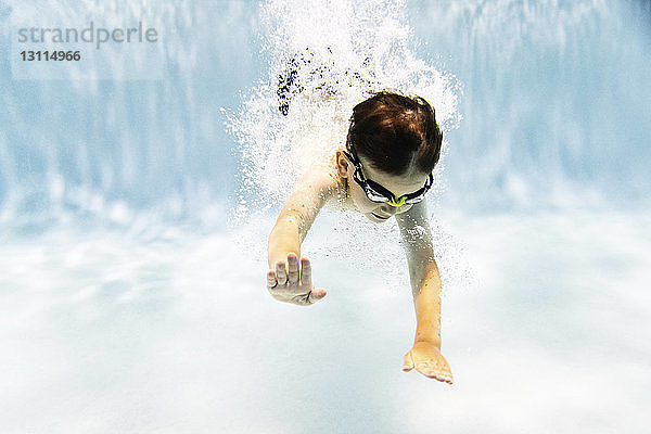 Junge ohne Hemd mit Schutzbrille beim Schwimmen im Schwimmbad