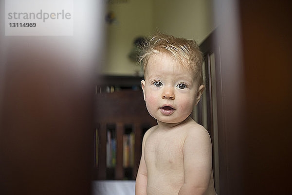 Hochwinkelansicht eines kleinen Jungen  der durch ein Fenster schaut  während er zu Hause steht