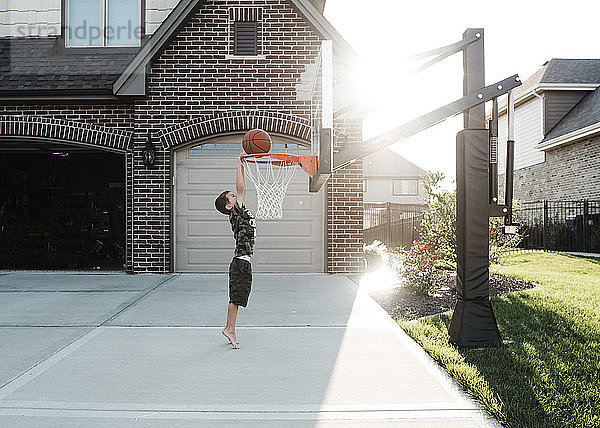 Seitenansicht eines Jungen  der im Hof Basketball spielt