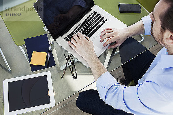 Draufsicht eines Geschäftsmannes mit Laptop am Konferenztisch