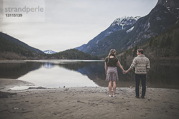 Rückansicht eines jungen Paares  das sich am Seeufer im Silver Lake Provincial Park an den Händen hält