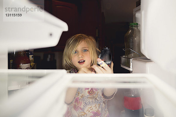 Süßes Mädchen schaut zu Hause in den Kühlschrank