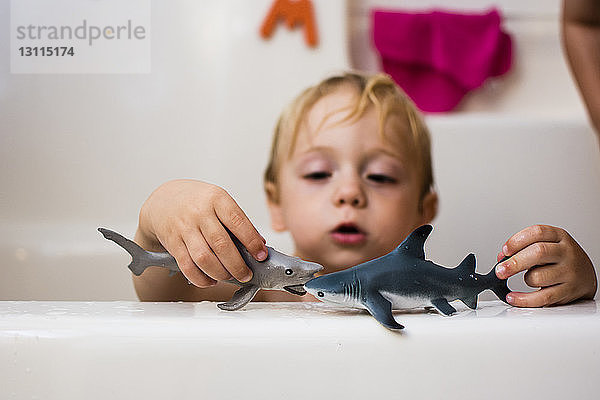 Nasser Junge spielt mit Spielzeug  während er in der Badewanne sitzt