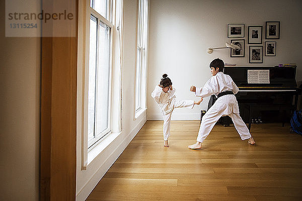 Geschwister üben zu Hause Karate am Fenster