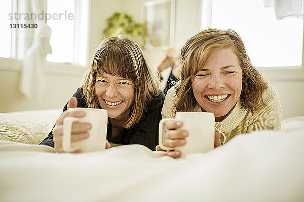 Lächelnde Schwestern liegen zu Hause auf dem Bett