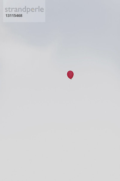 Tiefwinkelansicht eines roten Heliumballons in der Luft gegen den Himmel
