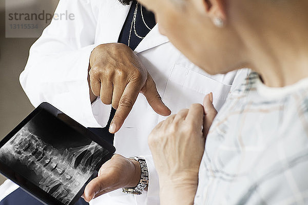Mittelteil des Arztes  der dem Patienten im Krankenhaus ein Röntgenbild zeigt