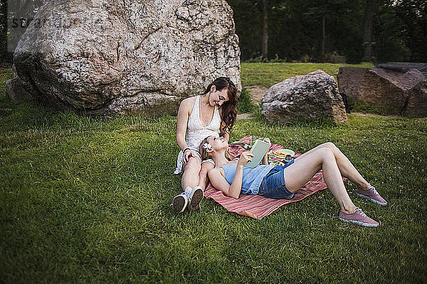 Glückliches lesbisches Paar entspannt auf Grasfeld im Park