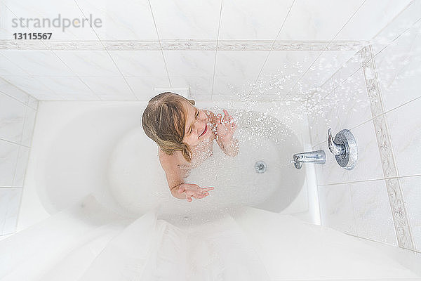 Weitwinkelansicht eines Mädchens mit geschlossenen Augen  das zu Hause in der Badewanne duscht