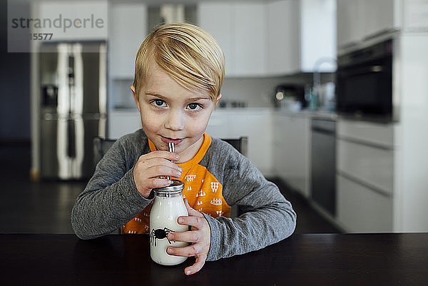 Porträt eines Jungen  der trinkt  während er am Tisch sitzt