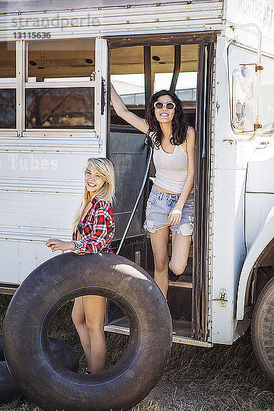 Porträt einer glücklichen Frau mit Freundin im alten Bus stehend