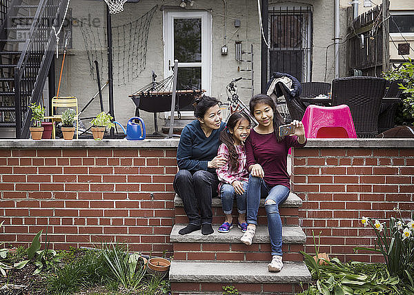 Familie  die vor dem Haus auf Stufen sitzend Selbsthilfe betreibt
