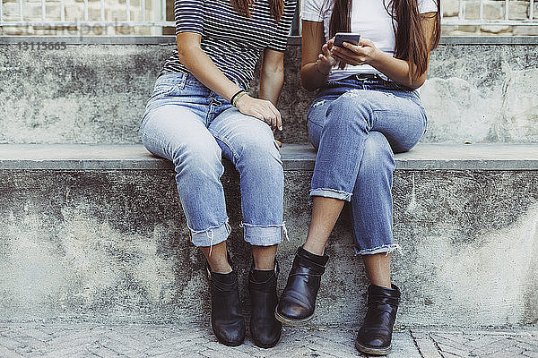 Niedriger Anteil von Freunden  die ein Mobiltelefon benutzen  während sie auf einer Treppe sitzen