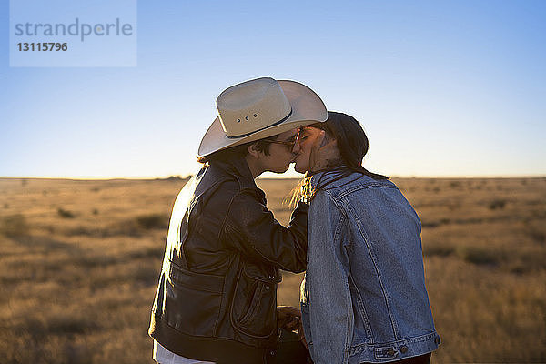 Seitenansicht eines Paares  das sich auf dem Spielfeld vor klarem Himmel küsst