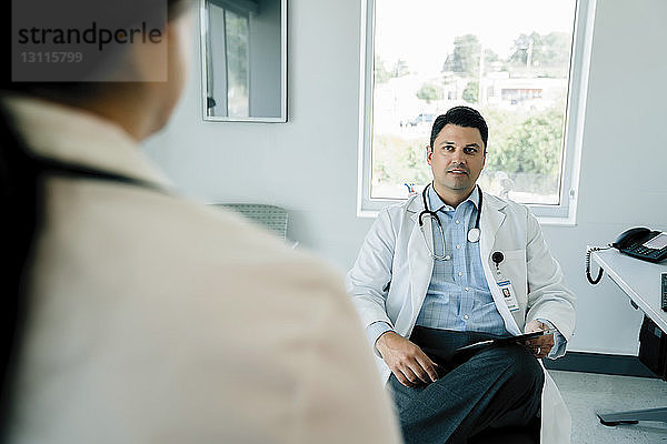 Arzt betrachtet Kollegin bei der Arbeit im Krankenhaus