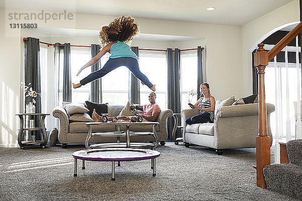 Eltern sehen Tochter zu Hause auf dem Trampolin springen
