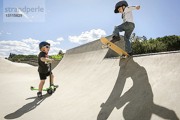 Junge sieht Freund an  der einen Stunt auf der Skateboard-Rampe vorführt